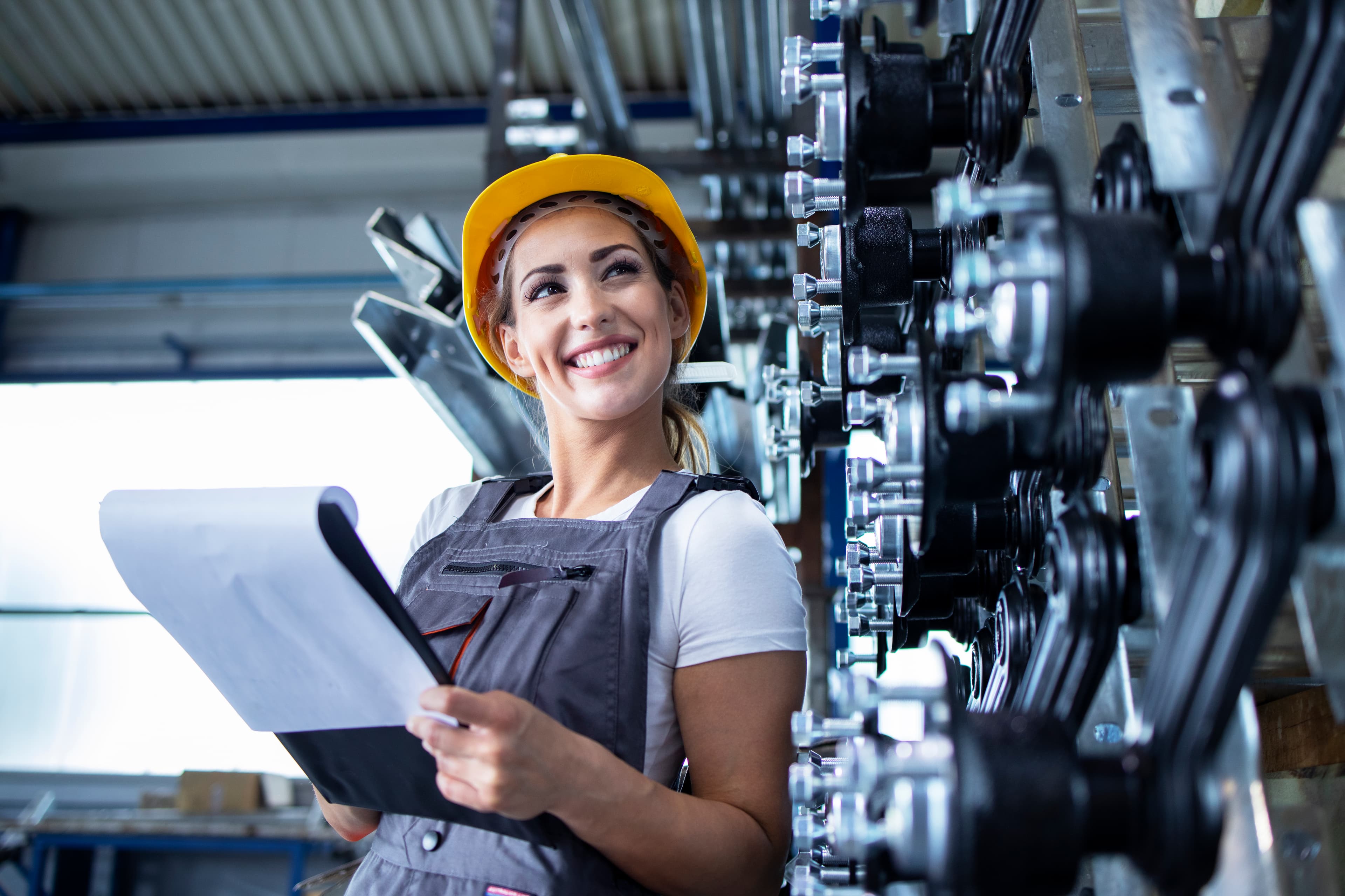 Profissional da indústria em uniforme e capacete conferindo produção