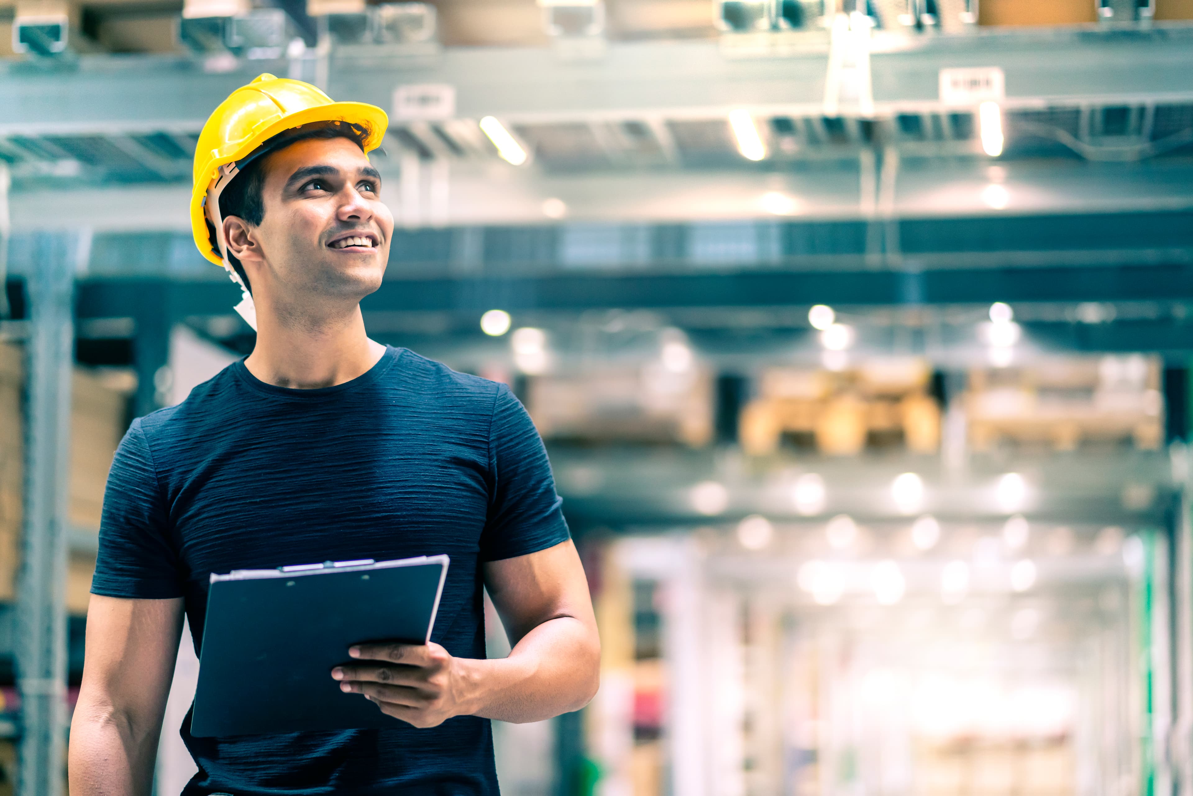 Engenheiro com capacete realizando conferência de estoque no armazém